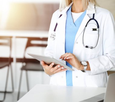 Güneşli klinikte bilinmeyen bir kadın doktor. Tablet bilgisayar kullanan kadın doktor, yakın plan.