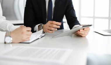 Bilinmeyen iş adamları modern ofiste tablet bilgisayar kullanıyorlar. İş adamı ya da erkek girişimci, çalışma masasında meslektaşıyla birlikte çalışıyor.