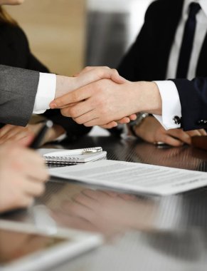 Bilinmeyen işadamı, modern ofiste iş arkadaşı ya da ortağıyla el sıkışıyor. Toplantıda iş adamları grubu