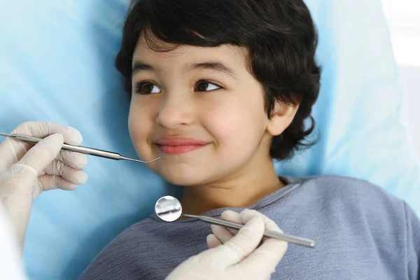 Cute arab boy sitting at dental chair with open mouth during oral checking up with doctor. Visiting dentist office. Stomatology concept — Stock Photo, Image