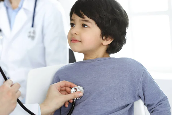 Orvos-nő sztetoszkóppal vizsgál meg egy gyermekbeteget. Aranyos arab fiú az orvosnál. Orvosi fogalom — Stock Fotó