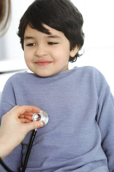 Médico-mujer examinando a un niño paciente por estetoscopio. Lindo chico árabe en la cita con el médico. Concepto de medicina — Foto de Stock