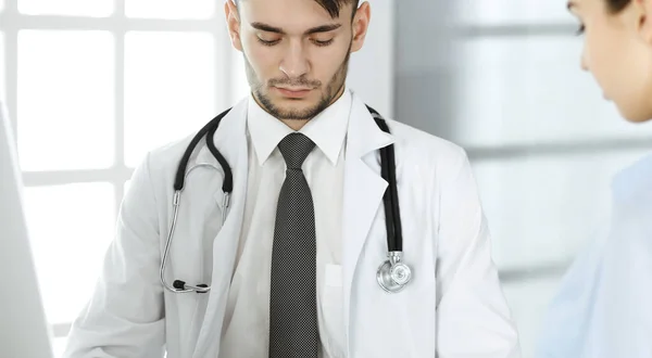 Dokter en patiënt. Artsenman vullen medicatie geschiedenis administratie formulier tijdens het zitten aan het glazen bureau in het medisch kantoor of kliniek. Concept geneeskunde en gezondheidszorg — Stockfoto