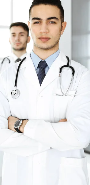 Médico árabe de pie con colega caucásico en consultorio médico o clínica. Equipo de médicos diversos, medicina y concepto de salud — Foto de Stock