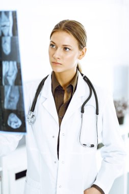 Kadın doktor hastanede röntgen filmini inceliyor. Klinikte çalışan cerrah ya da ortopedist.