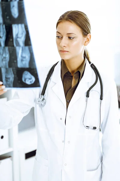 Woman-doctor examining x-ray picture in hospital. Surgeon or orthopedist at work in clinic — Stock Photo, Image