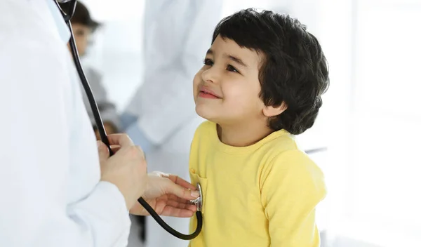 Mujer-médico examinando a un niño paciente por estetoscopio. Lindo chico árabe en la cita con el médico. Medicina ayuda concepto — Foto de Stock