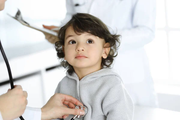 Vrouwendokter die een kindpatiënt onderzoekt met stethoscoop. Leuke Arabische peuter op afspraak bij de dokter. Geneesmiddelenconcept — Stockfoto