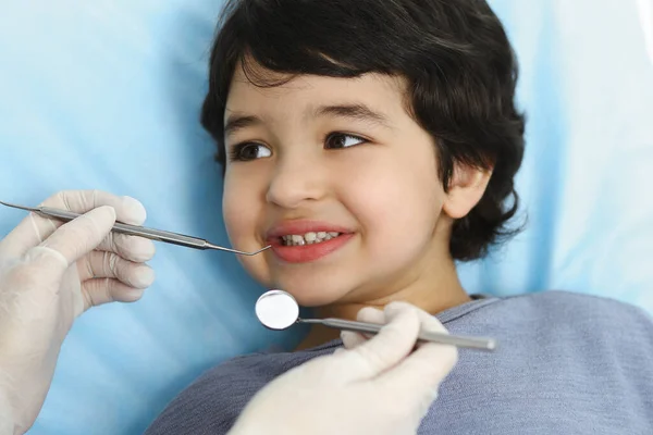 Cute arab boy sitting at dental chair with open mouth during oral checking up with doctor. Visiting dentist office. Stomatology concept — Stock Photo, Image