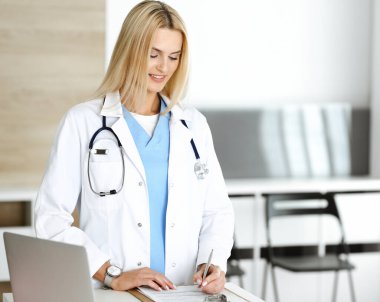 Hastanedeki doktor kadın mesleğinden dolayı heyecanlı ve mutlu. Sarışın doktor ilaç kayıtlarını ve sınav sonuçlarını pano kullanarak kontrol ediyor. Tıp ve sağlık hizmetleri kavramı