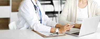 Bilinmeyen kadın doktor oturuyor ve kadın hastayla iletişim kuruyor. Doktor tıbbi geçmişi ve muayene sonuçlarını yakından kontrol ediyor. Sağlık hizmetleri kavramı