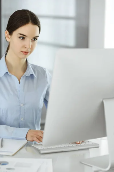 Ділова жінка працює з комп'ютером за скляним столом в сучасному офісі. Студентська дівчина готує презентацію або букмекер, роблячи баланс. Податкова та аудиторська концепція — стокове фото