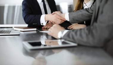 Bilinmeyen işadamı, modern ofiste iş arkadaşı ya da ortağıyla el sıkışıyor. Toplantıda iş adamları grubu