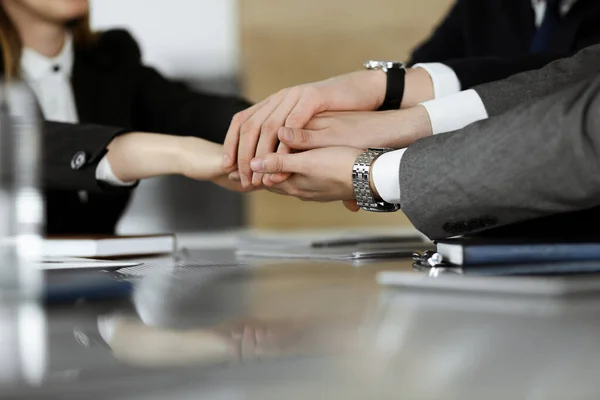 Unknown business people group joining hands in modern office. Businessmen and women making circle with their hands as a team, close-up