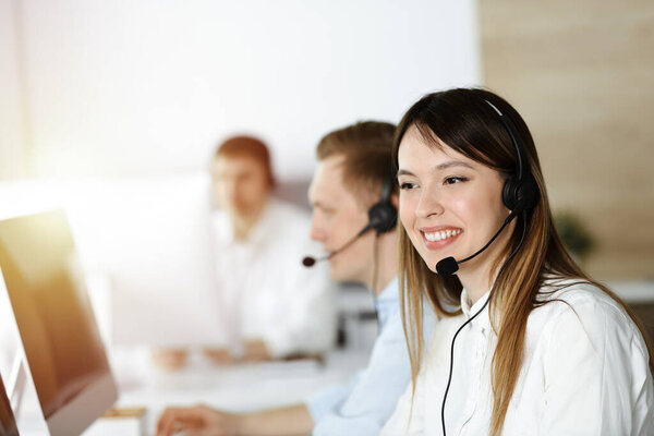 Asian woman working at customer service office. Business concept. Group of diverse operators at work in sunny call center.