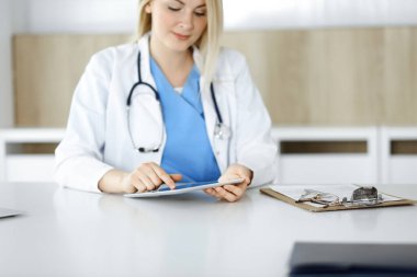 Bilinmeyen kadın doktor klinikte duruyor ve tablet bilgisayar kullanıyor, yakın plan. Veriler ve tıp ve sağlık hizmetlerindeki en iyi hizmet