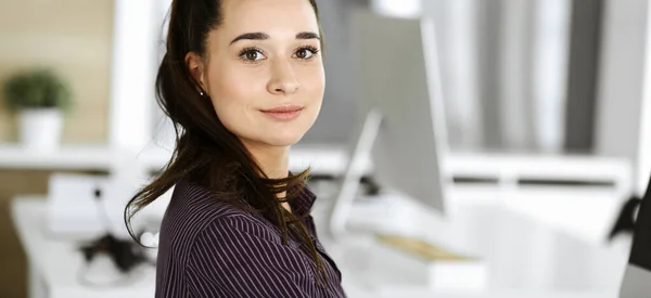 Affärskvinna som använder dator på arbetsplatsen på modernt kontor. Brunett sekreterare eller kvinnlig advokat ler och ser glad. Arbeta för njutning och framgång — Stockfoto