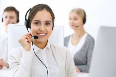 Merkezi ara. Bir grup operatör iş başında. Müşteri hizmetleri beyaz ofisindeki kulaklıklı güzel bayan resepsiyoniste odaklan. İş konsepti