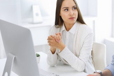 İş kadını ve erkek ofiste bilgisayar başında oturuyor ve çalışıyor. İş arkadaşları toplantıda bir şey tartışıyor. Şirket takım çalışması ve ortaklık kavramları