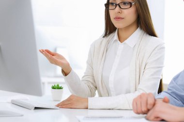 İş kadını ve erkek ofiste bilgisayar başında oturuyor ve çalışıyor. İş arkadaşları toplantıda bir şey tartışıyor. Şirket takım çalışması ve ortaklık kavramları