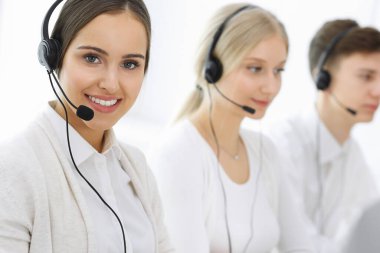 Merkezi ara. Bir grup operatör iş başında. Müşteri hizmetleri beyaz ofisindeki kulaklıklı güzel bayan resepsiyoniste odaklan. İş konsepti