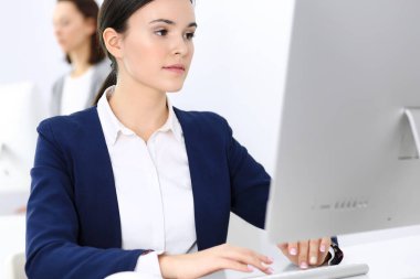 Ofiste bilgisayarla çalışan bir iş kadını, arka planda çalışan bir iş arkadaşı. Masada otururken avukatın ya da muhasebecinin vesikalığı.