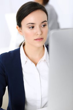 Ofiste bilgisayarla çalışan bir iş kadını, arka planda çalışan bir iş arkadaşı. Masada otururken avukatın ya da muhasebecinin vesikalığı.