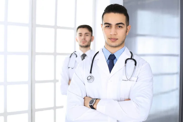 Medico arabo in piedi con collega caucasico in studio medico o in clinica. Diversi medici team, medicina e concetto di assistenza sanitaria — Foto Stock