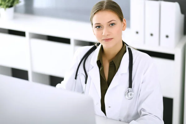 Médico escribiendo en el ordenador PC mientras está sentado en el escritorio en la oficina del hospital. Mujer médica en el trabajo. Datos en medicina y asistencia sanitaria — Foto de Stock