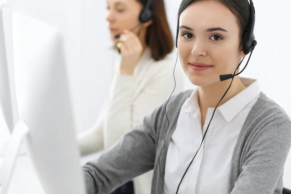 Centro de llamadas. Hermosa recepcionista mujer sentada en auriculares en la oficina de servicio al cliente. Grupo de operadores en el trabajo. Concepto empresarial —  Fotos de Stock