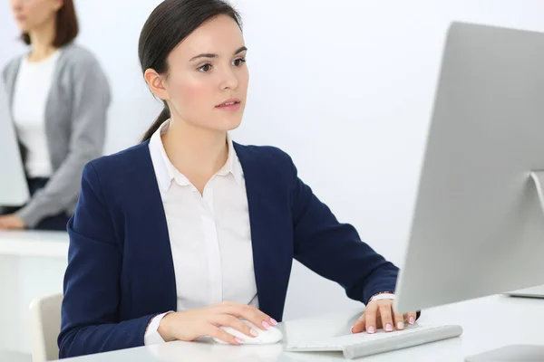 Mujer de negocios que trabaja con la computadora en la oficina, colega de fondo. Imagen de Abogado o Contador en el trabajo mientras está sentado en el escritorio —  Fotos de Stock