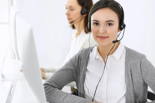 Centro de llamadas. Hermosa recepcionista mujer sentada en auriculares en la oficina de servicio al cliente. Grupo de operadores en el trabajo. Concepto empresarial —  Fotos de Stock