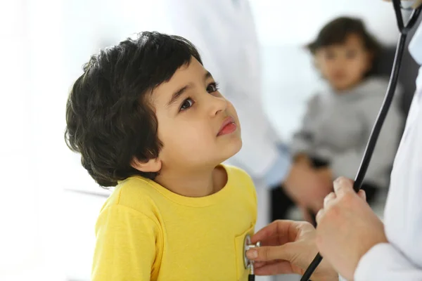 Médico examinando a un niño paciente por estetoscopio. Lindo chico árabe en la cita con el médico. Concepto de medicina y salud —  Fotos de Stock