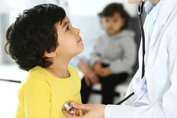 Arzt untersucht eine Kinderpatientin mit einem Stethoskop. Netter arabischer Junge beim Arzttermin. Medizin und Gesundheitskonzept — Stockfoto