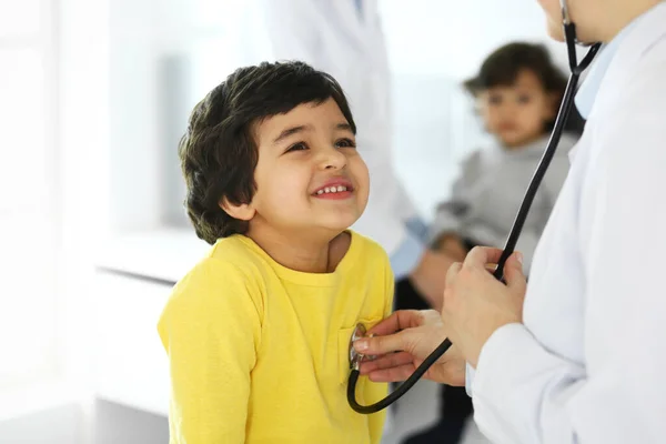 Médico examinando a un niño paciente por estetoscopio. Lindo chico árabe en la cita con el médico. Concepto de medicina y salud — Foto de Stock