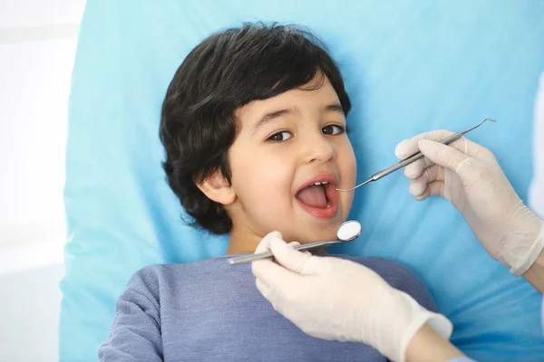 医生进行口腔检查时，坐在牙椅上张开嘴的阿拉伯小男孩。去看牙医医学和口腔医学概念 — 图库照片