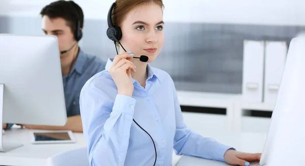 Group of operators at work. Call center. Focus on beautiful woman receptionist in headset at customer service. Business concept and casual clothing style — Stock Photo, Image