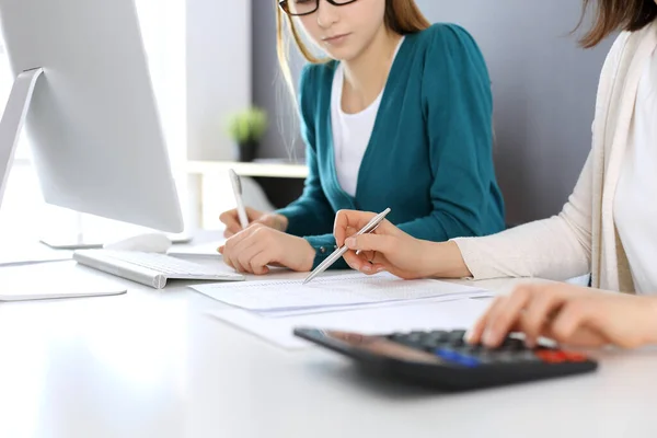 Contabilista verificando ficha financeira ou contando por calculadora de renda para a forma de imposto, mãos close-up. Mulher de negócios sentada e trabalhando com colega na mesa no escritório. Conceito de auditoria — Fotografia de Stock