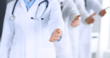 Bir grup modern doktor bir takım olarak el sıkışmak ya da hayat kurtarmak için yardım eli uzatıyorlar. Doktorlar hastaları muayene etmeye ve yardım etmeye hazır. Tıbbi yardım, sigorta