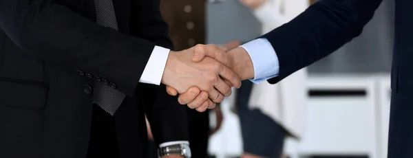 Les gens d'affaires se serrent la main après la signature du contrat au bureau en verre dans un bureau moderne. Homme d'affaires inconnu, entrepreneur masculin avec des collègues lors de réunions ou de négociations. Travail d'équipe, partenariat et — Photo