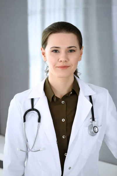 Doctora mujer feliz y alegre mientras está de pie en la oficina del hospital. Servicio médico perfecto en la clínica. Concepto de medicina y salud — Foto de Stock