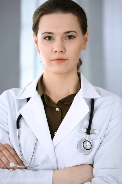 Doctora mujer feliz y alegre mientras está de pie en la oficina del hospital. Servicio médico perfecto en la clínica. Concepto de medicina y salud — Foto de Stock