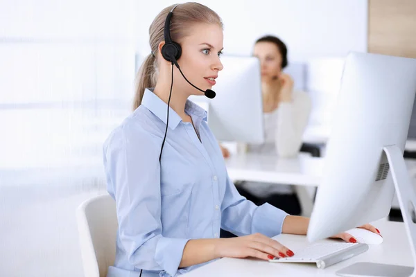 Call center office. Beautiful blonde woman using computer and headset for consulting clients online. Group of operators working as customer service occupation. Business people concept — Stock Photo, Image