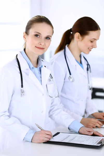 Grupo de médicos en el trabajo en el hospital. Médico llenando documentos médicos o receta mientras está de pie en la recepción. Datos en medicina y concepto de salud — Foto de Stock