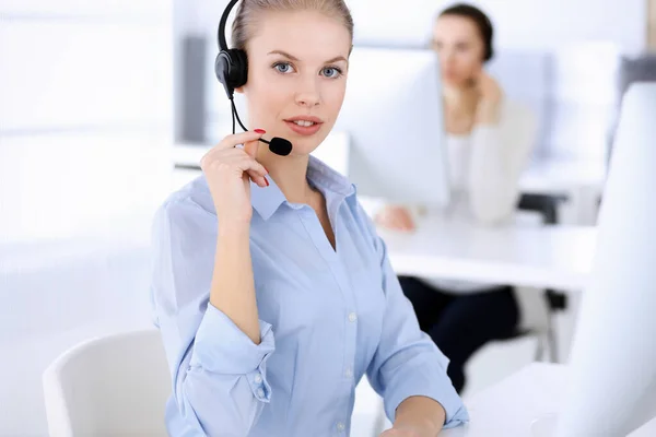 Call center office. Beautiful blonde woman using computer and headset for consulting clients online. Group of operators working as customer service occupation. Business people concept Royalty Free Stock Photos