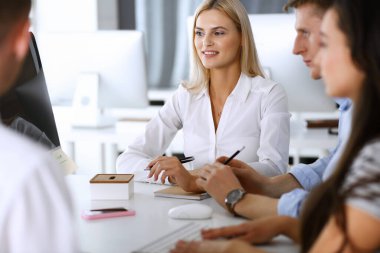 Bir grup iş adamı toplantıda soruları tartışıyor. Ofis görüşmelerinde iş arkadaşına gülümseyen sarışın iş kadınının vesikalığı. Şirket işgalinde takım çalışması ve işbirliği