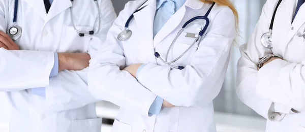 Moderne dokters staan als een team met gekruiste armen in het ziekenhuiskantoor, close-up. Artsen klaar om patiënten te onderzoeken en te helpen. Medische hulp, verzekering in de gezondheidszorg, beste behandeling en — Stockfoto