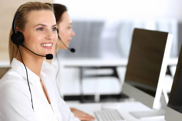 Centro de atendimento. Mulher de negócios feliz e animado usando fone de ouvido enquanto consulta clientes online. Escritório de atendimento ao cliente ou departamento de telemarketing. Grupo sorridente de operadores no trabalho — Fotografia de Stock