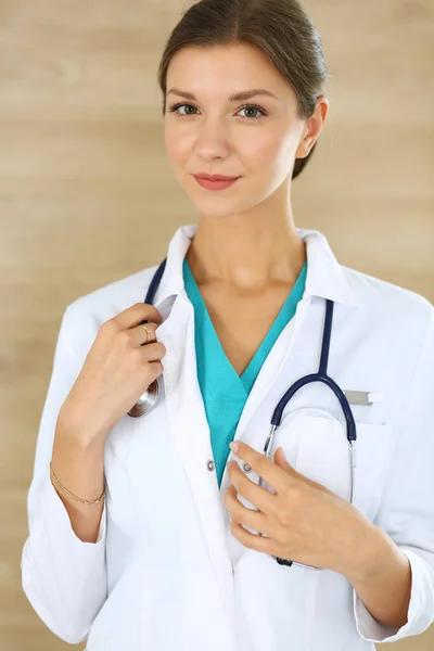 Γιατρός γυναίκα στέκεται και κοιτάζει την κάμερα. Γιατρός στη δουλειά, πορτραίτο στούντιο στο ιατρικό υπόβαθρο. Ιατρική και υγειονομική περίθαλψη — Φωτογραφία Αρχείου