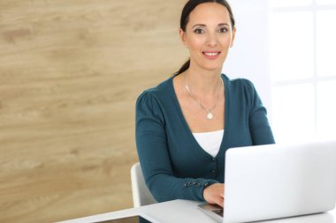 Modern ofisteki masada otururken bilgisayarla çalışan neşeli gülümseyen iş kadını. Orta yaşlı kadın avukat ya da denetçi. İş adamları konsepti